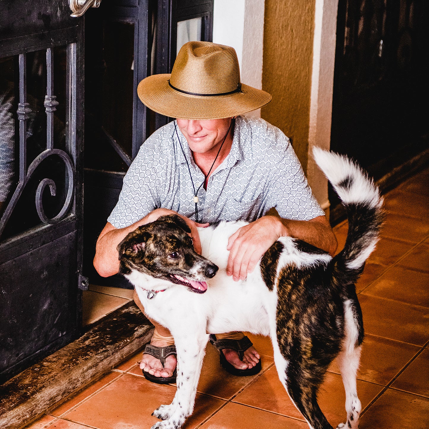 Man wearing Logan fedora sun hat with brown and white dog