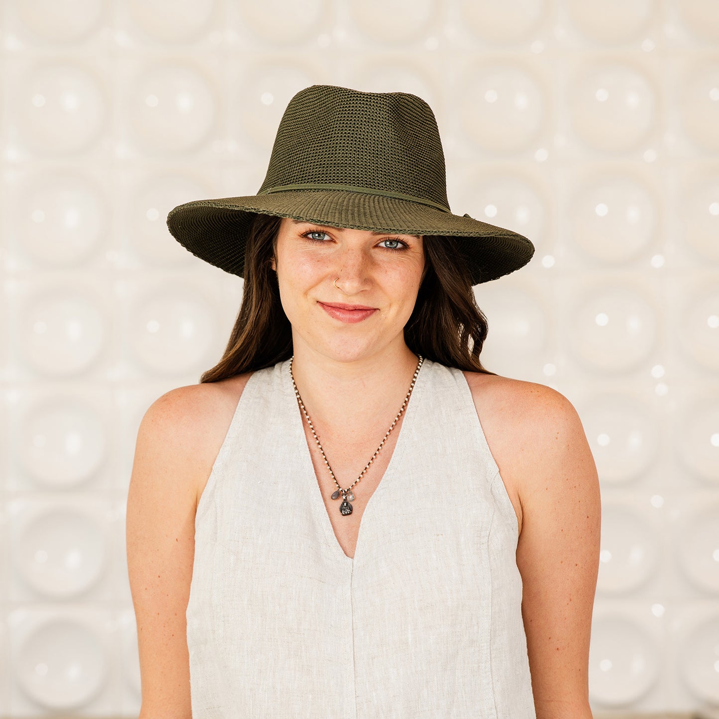 Woman wearing a Victoria Fedora sun hat against a textured background, Olive