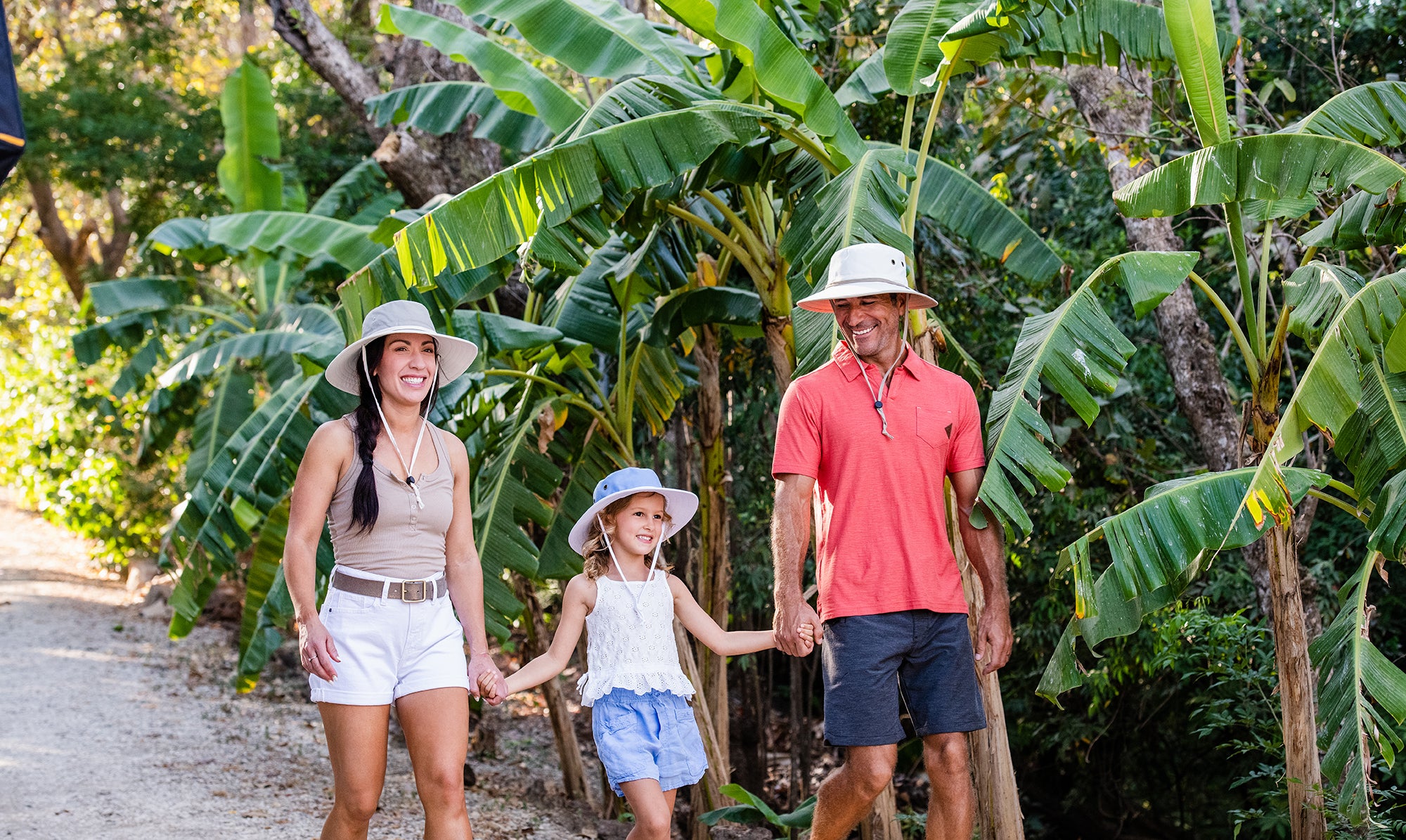 Family holding hands while wearing summer sun hats 