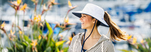 Woman in a garden wearing a wide brim ponytail sun hat