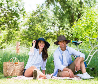 Man and woman sitting outside while wearing big wide brim sun hats