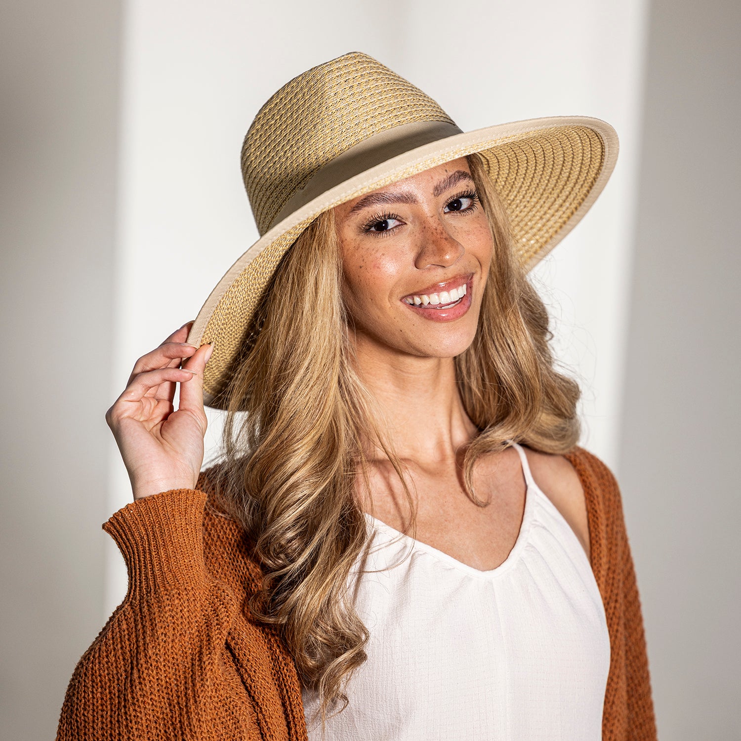 Woman wearing the Bali fedora and brown cardigan against a plain background