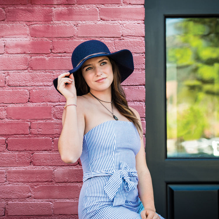 Woman Wearing a Wallaroo Cambria Navy Wool UPF Wide Brim Felt Sun Hat in front of a Brick Building