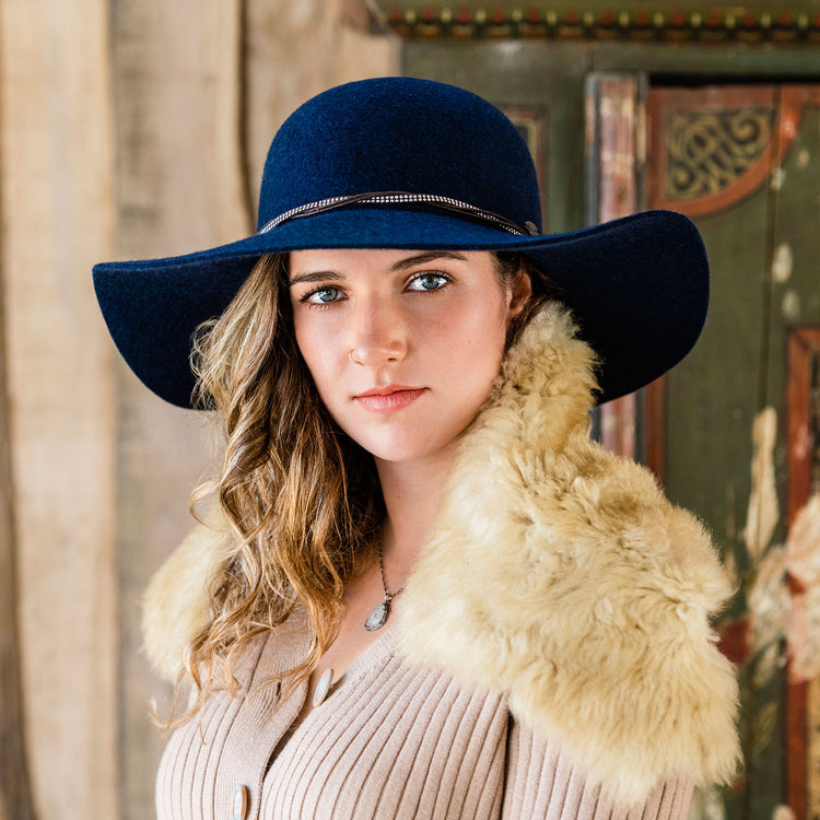 Woman wearing the Wallaroo Victoria Sun Hat, combining lightweight poly-straw material and UPF 50 protection for cooler seasonal days, Navy