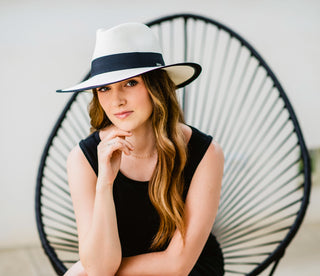 Woman sitting while wearing a wide brim sun hat 