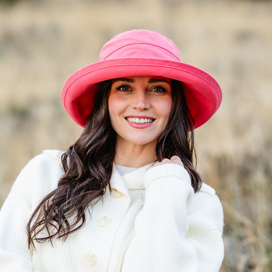 Woman wearing a big wide brim UPF sun hat outside, Coral