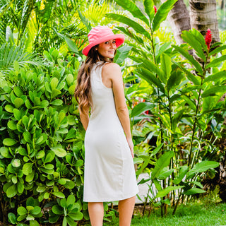 Woman enjoying a garden walk in the Wallaroo Casual Travelers Wide Brim Sun Hat, blending fashionable sun protection with a natural outdoor experience, Cotton Canvas-Coral