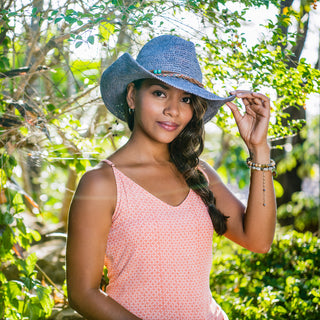 Woman enjoying a sunny picnic in a city park, wearing the Wallaroo Catalina Cowboy Raffia Sun Hat, combining a relaxed outdoor look with reliable sun protection, Dusty Blue