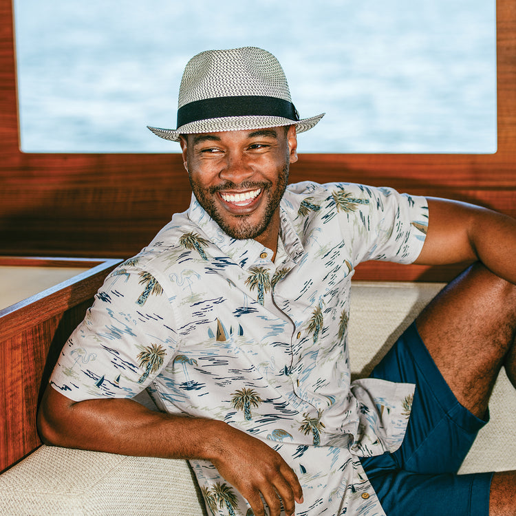 Man wearing the Wallaroo Unisex Charlie Fedora Sun Hat during a day on the boat, showcasing short brim sun protection for both men and women in sunny conditions, Ivory/Black