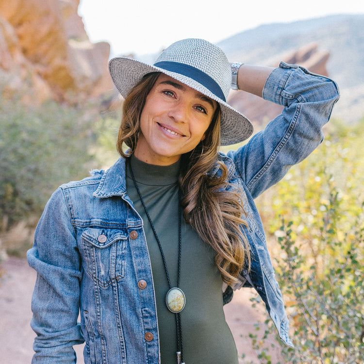 A fit woman wearing the Wallaroo Unisex Charlie Fedora Sun Hat during a weekend hike, offering lightweight comfort, UPF 50+ sun protection, and a fashionable design for active lifestyles, Ivory/Black