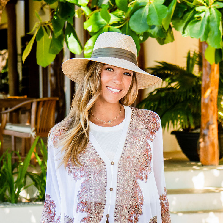 Woman relaxing by a pool in the Wallaroo Charlotte sun hat, offering breathable UPF 50+ sun protection and a sleek design perfect for resort or vacation life, Natural