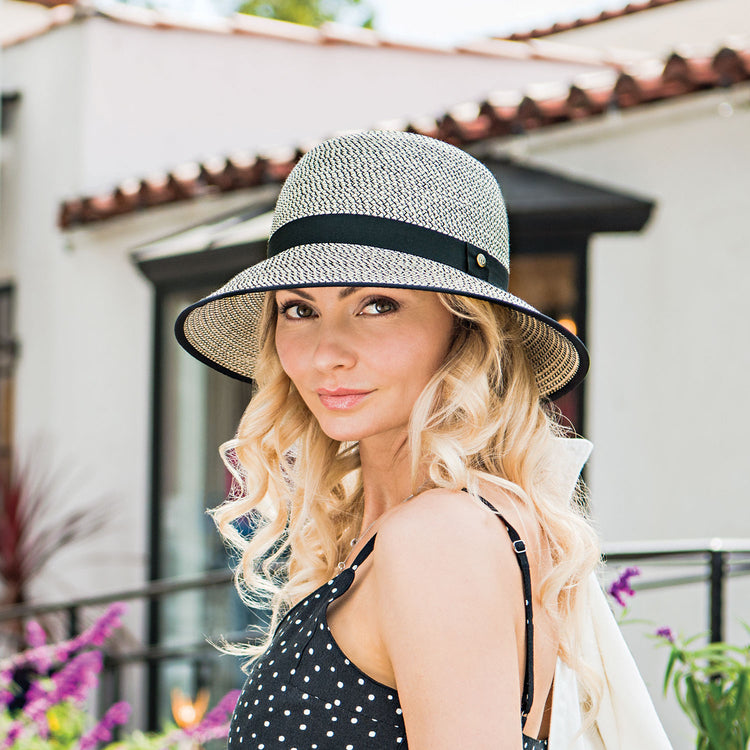 Woman exploring a farmers market in the Wallaroo Darby Wide Brim Cloche Sun Hat, combining UV protection and elegant style for a sunny day in the city, Ivory/Black