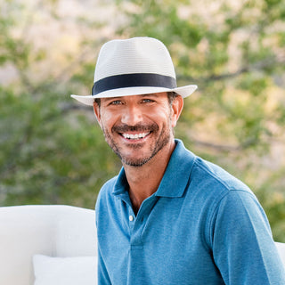 Man wearing the Wallaroo Del Mar sun hat in Ivory, relaxing outdoors, showcasing a short brim, UPF 50+ sun protection, and effortless summer style.