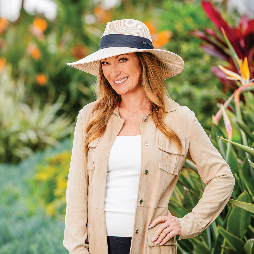 Actress Jane Seymour wearing a wide-brimmed Elise hat and beige jacket in a garden setting