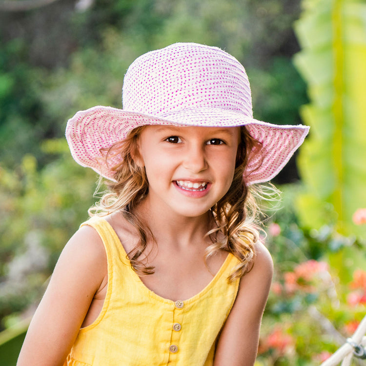 Kid wearing a packable summer sun hat for kids, White/Fuchsia dots