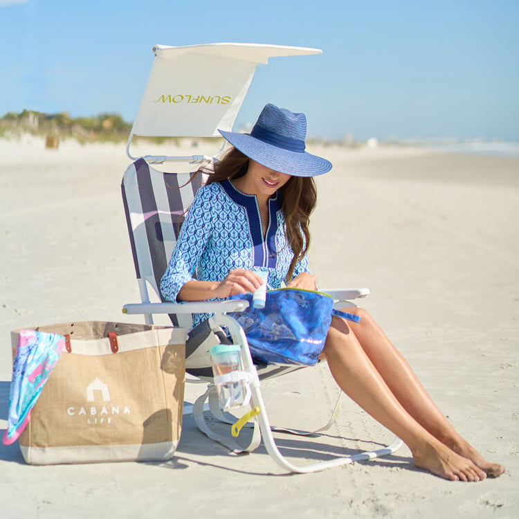 Woman enjoying a peaceful moment on the beach in the Wallaroo Klara Fedora Sun Hat, providing UPF 50+ protection and wide brim style for ultimate relaxation, Navy