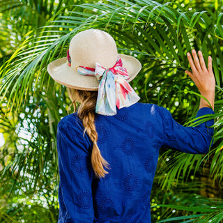 Woman seen from behind, wearing the Packable Big Wide Brim Lady Jane UPF Summer Sun Hat by Wallaroo, showcasing the beautiful Jane Seymour artwork on the trim, Natural-Leaves