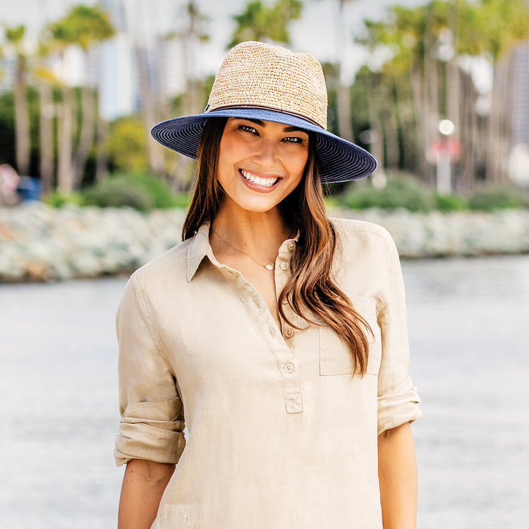 Woman on a sunny beach, wearing the natural-fiber Wallaroo Laguna Wide Brim Fedora, ideal for water-side activities with broad sun coverage and timeless style, Navy