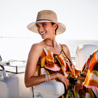 Woman relaxing on a boat in the Wallaroo Women’s Laguna Wide Brim Fedora, for effective UV protection, Natural