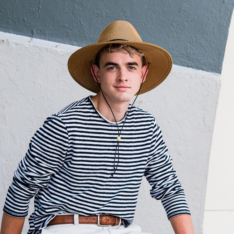 Man strolling protected from the elements in the Wallaroo Logan Fedora Sun Hat, ideal for festivals with a classic design, Camel