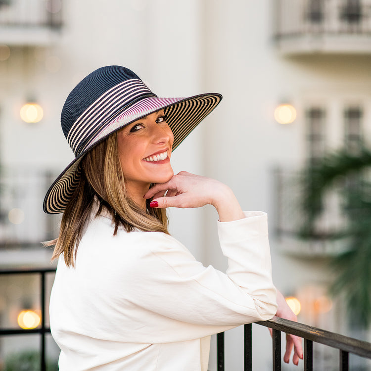 Woman sightseeing in a bustling city, protected from the sun with the Wallaroo Marseille Wide Brim Hat, blending functionality with timeless fashion, Black/Natural