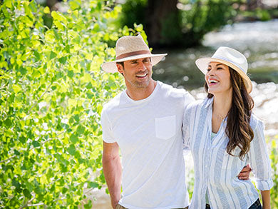 man and woman smiling while wearing summer sun hats