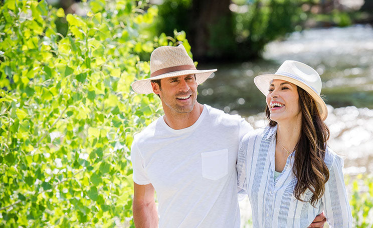 man and woman smiling while wearing summer sun hats