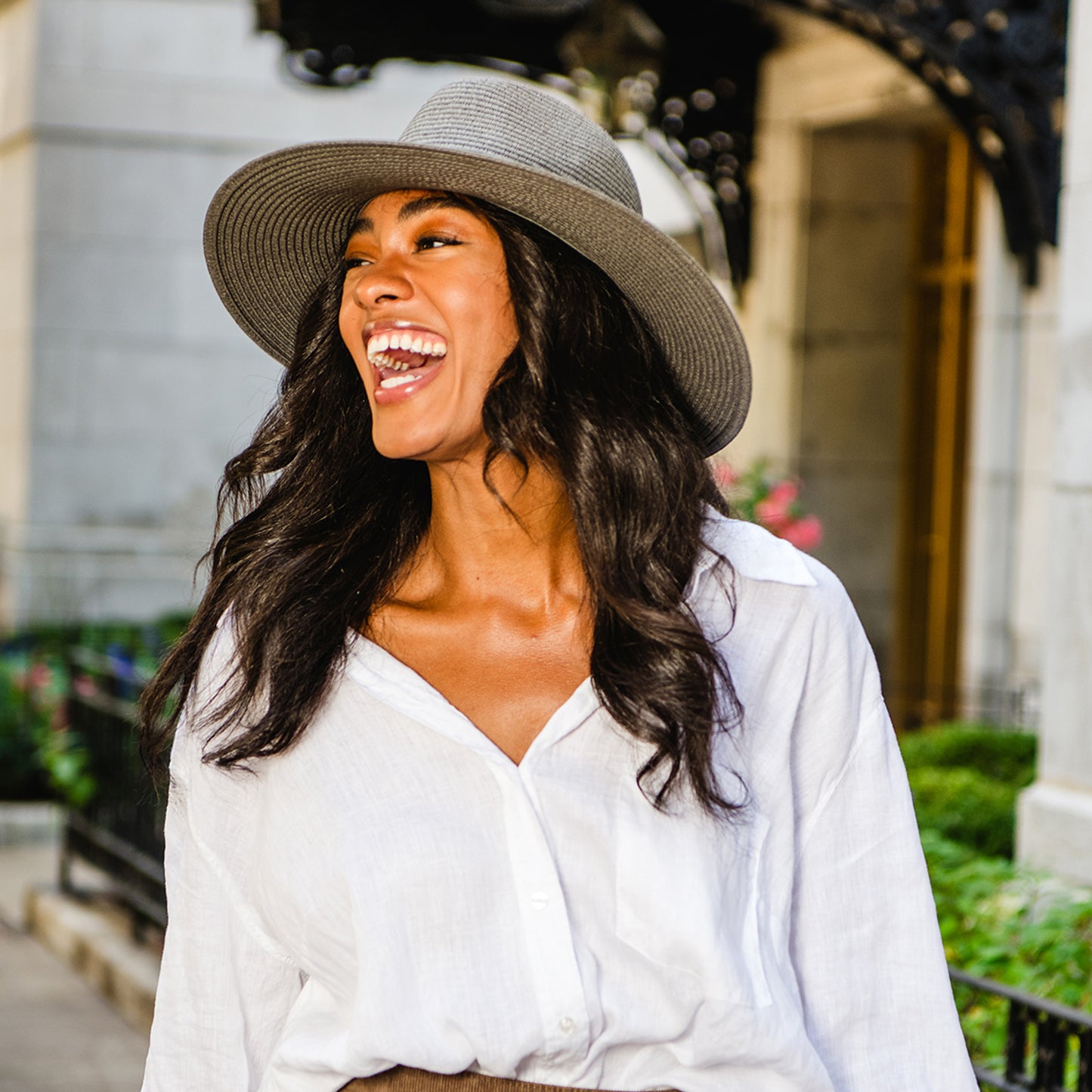 Woman taking a stroll, wearing the Wallaroo Montecito wide brim sun hat, offering both sun protection and urban sophistication during her cultural outing, Graphite