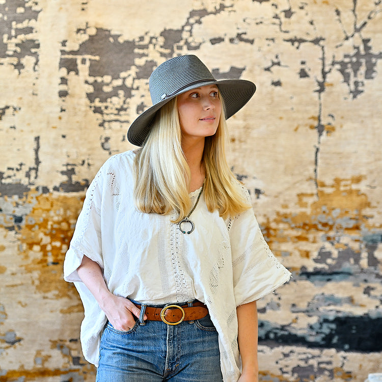 Woman walking through an artsy city district, wearing the Wallaroo Montecito wide brim UPF 50 sun hat for shade and comfort on her urban exploration, Graphite