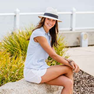 Woman sitting in a park, wearing the Wallaroo Monterey sun hat, providing medium brim coverage and UPF 50+ sun protection, 'Natural/Black'