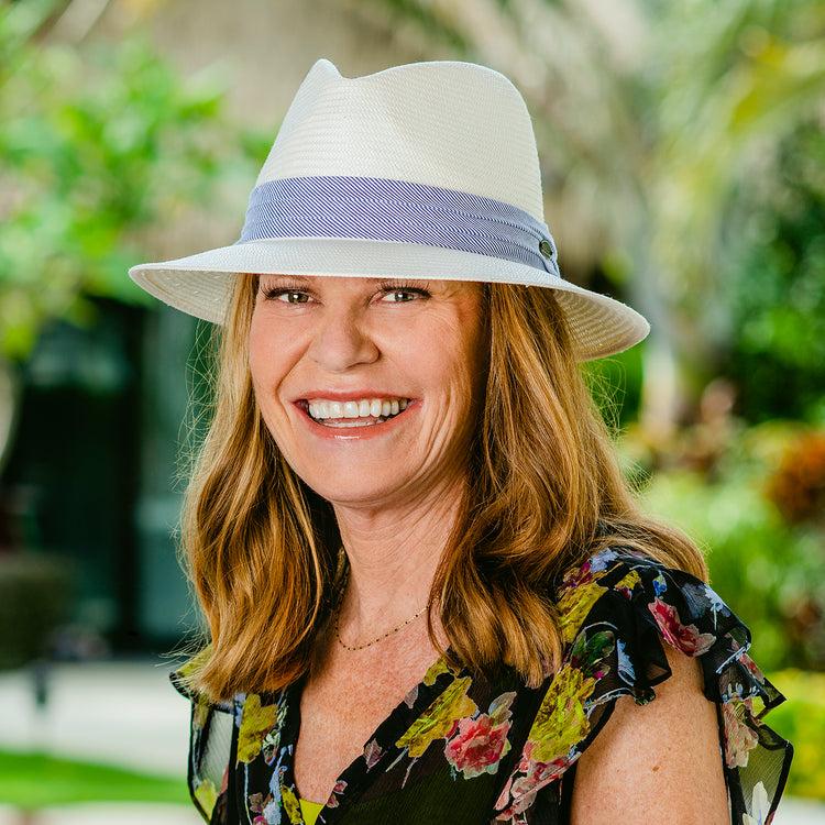 Woman exploring a city, wearing the Wallaroo Monterey sun hat, featuring a medium brim and SPF 50+ protection, perfect for sunny urban settings, 'Natural w/Blue Pinstripe'