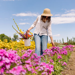 Woman enjoying a day gardening, wearing the Wallaroo Montecito wide brim sun hat, offering both sun protection and urban sophistication during her cultural outing, Natural