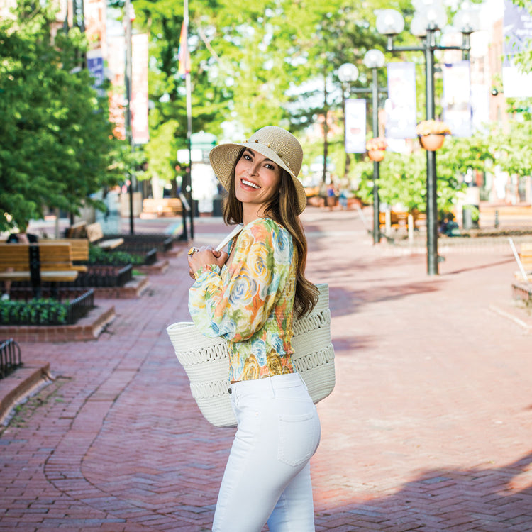 Woman strolling through a downtown Boulder Colorado, wearing the Wallaroo Montecito wide brim sun hat to stay cool and stylish on her urban outing, Natural