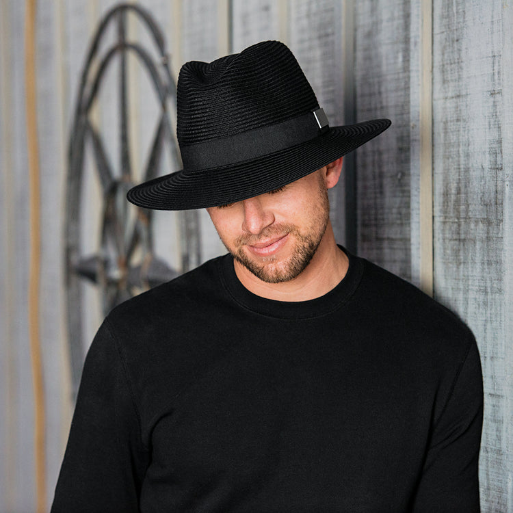 Man enjoying a sunny afternoon at a rustic barn, wearing the Carkella Men’s Palm Beach Panama Fedora Sun Hat, wide brim with UPF 50+ for breathable sun protection on hot summer days, Black