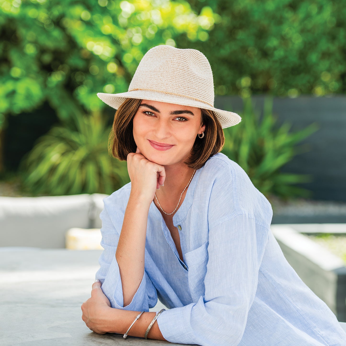 Woman wearing Rio fedora sun hat leaning on counter, White/Beige