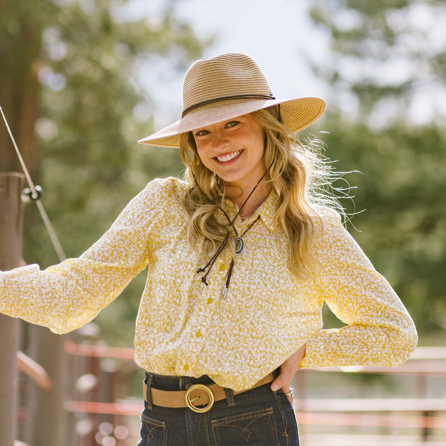 Woman wearing a yellow floral blouse and Sanibel wide-brimmed hat outdoors, Camel