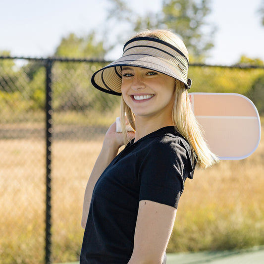 Woman taking a break from a pickle ball game, wearing the Wallaroo Savannah Visor, featuring a wide brim and UPF 50+ sun protection for ultimate comfort on sunny days, Camel/Black