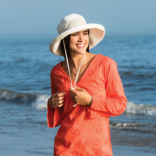 Woman Wearing a Packable Wide Brim Seaside UPF Sun Hat with Chinstrap in Natural from Wallaroo