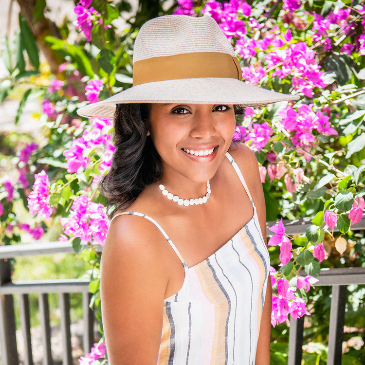 Woman standing in a garden wearing a wide brim fedora St. Lucia sun hat by Wallaroo, Mixed Beige