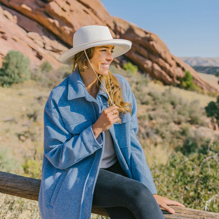 Woman enjoying a sunny day in Colorado, shaded by the Wallaroo Stevie Fedora Sun Hat with a wide brim and chin strap, perfect for sunny and breezy outdoor adventures, Ivory