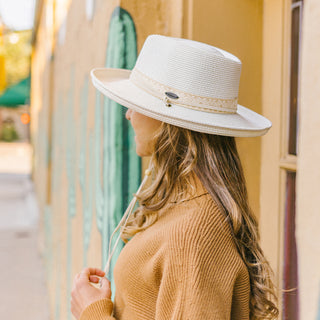 Woman wearing the Wallaroo Stevie Wide Brim Fedora Hat, providing stylish sun protection with a chin strap for stability in windy conditions, Ivory