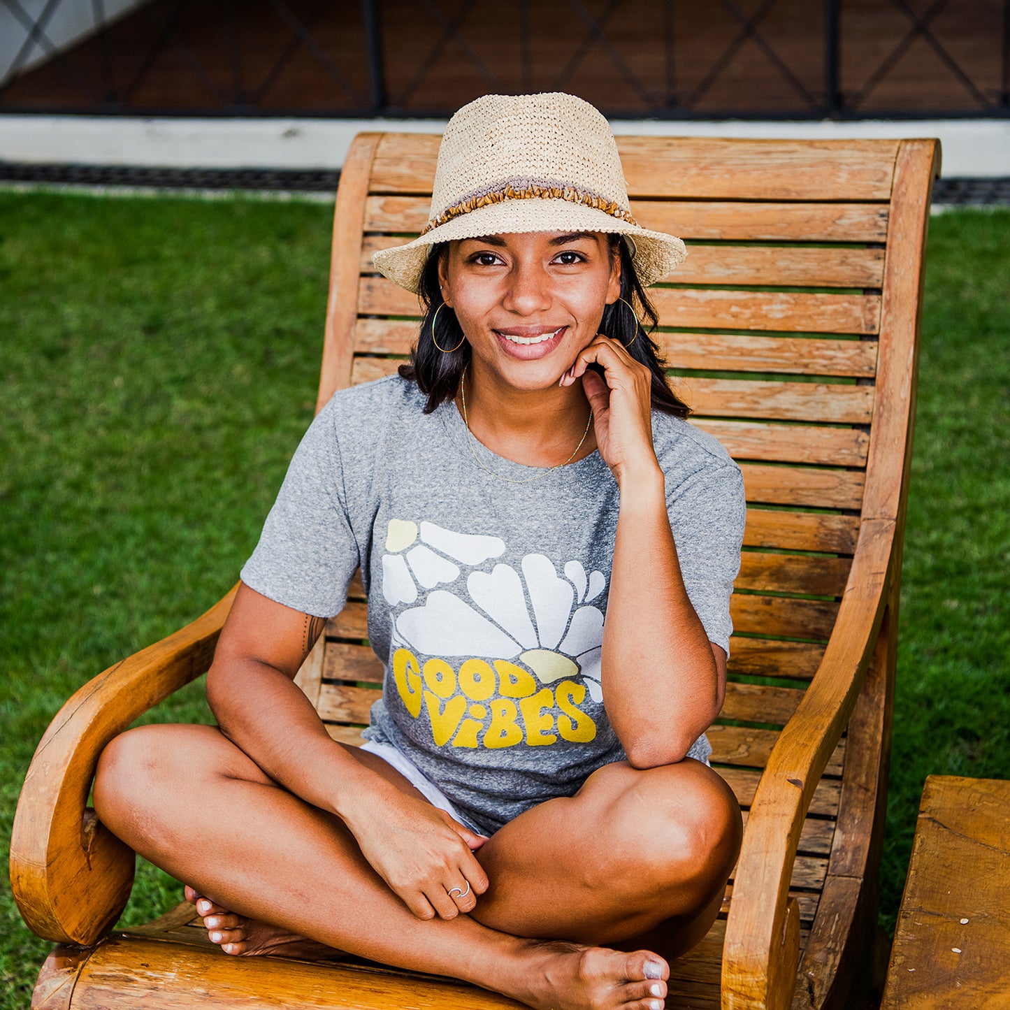 A sitting woman relaxing, wearing the Wallaroo Women’s Tahiti Trilby Hat, a breathable and stylish natural straw sun hat for warm urban getaways, Taupe