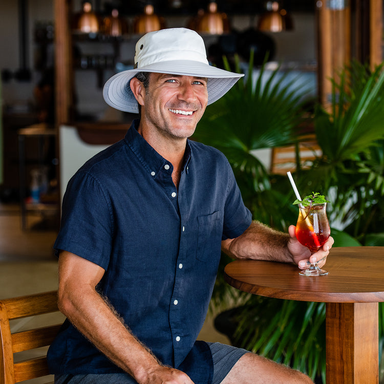 Man wearing the Carkella Tahoe Bucket Sun Hat enjoying a drink, offering lightweight sun protection and style for long rounds of golf under the sun, White/Grey