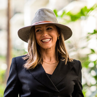 Woman in a mountain town, wearing the Wallaroo Women’s Telluride Fedora Sun Hat, a stylish sun hat for sunny summer adventures, Sage