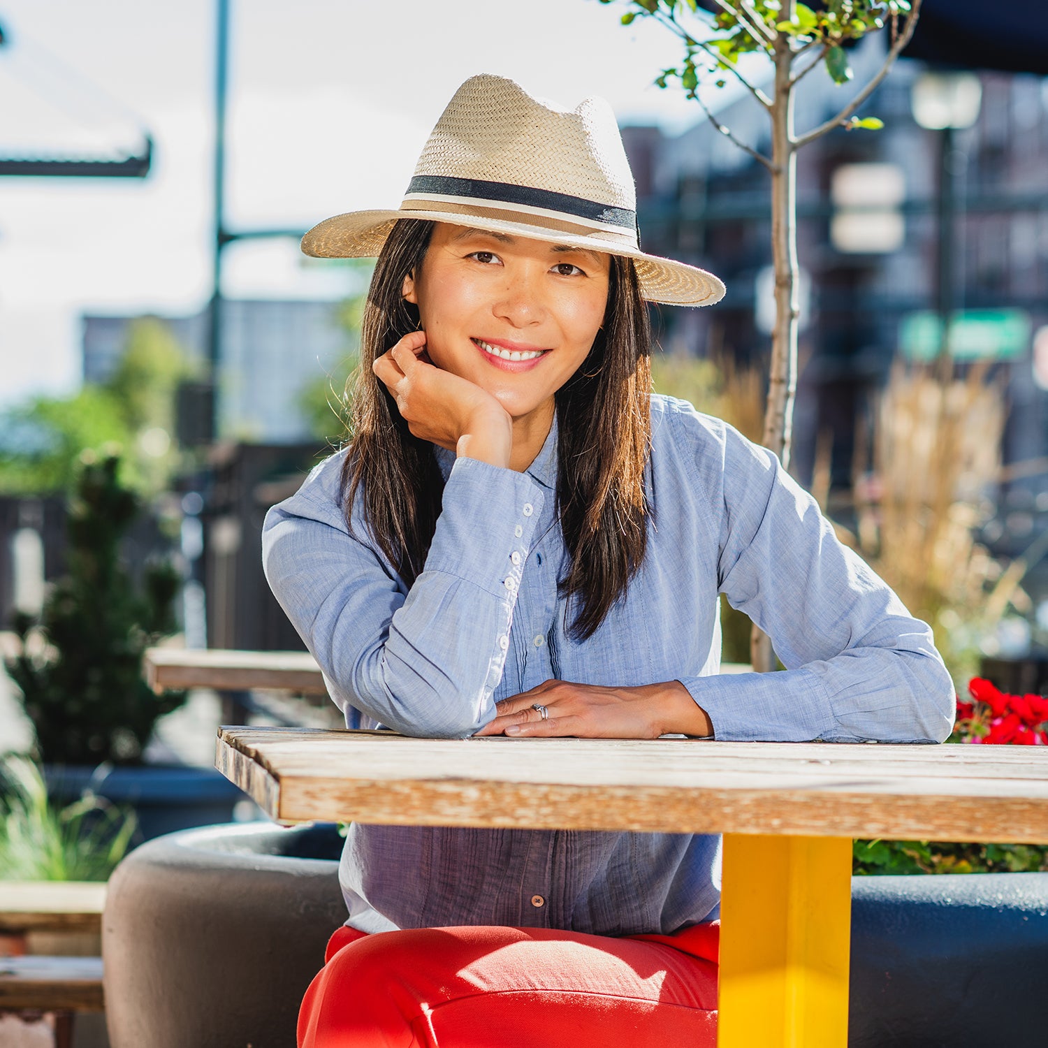 Woman sitting at an outdoor table wearing the unisex Turner fedora. 