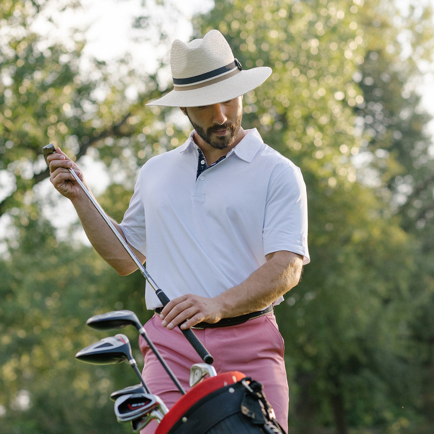 Man enjoying a casual game of golf wearing the Wallaroo Men’s Turner Sun Hat, providing timeless style and sun protection, Ivory