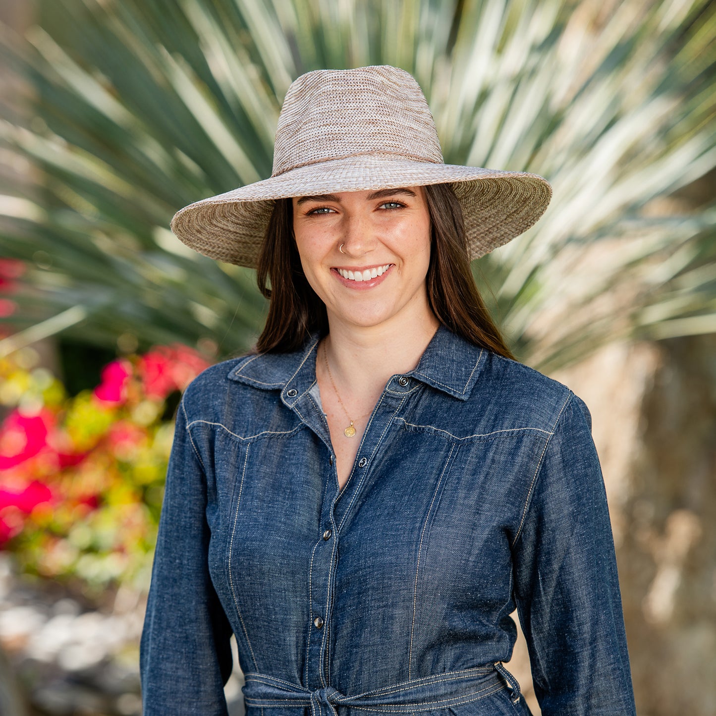 Woman wearing a denim dress and Victoria Fedora Diva wide-brimmed sun hat with a blurred natural background, Mixed Camel