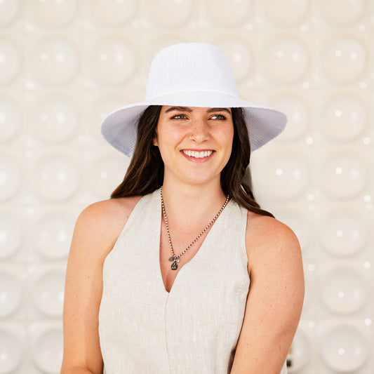 Woman wearing a Victoria Fedora sun hat against a textured background, White