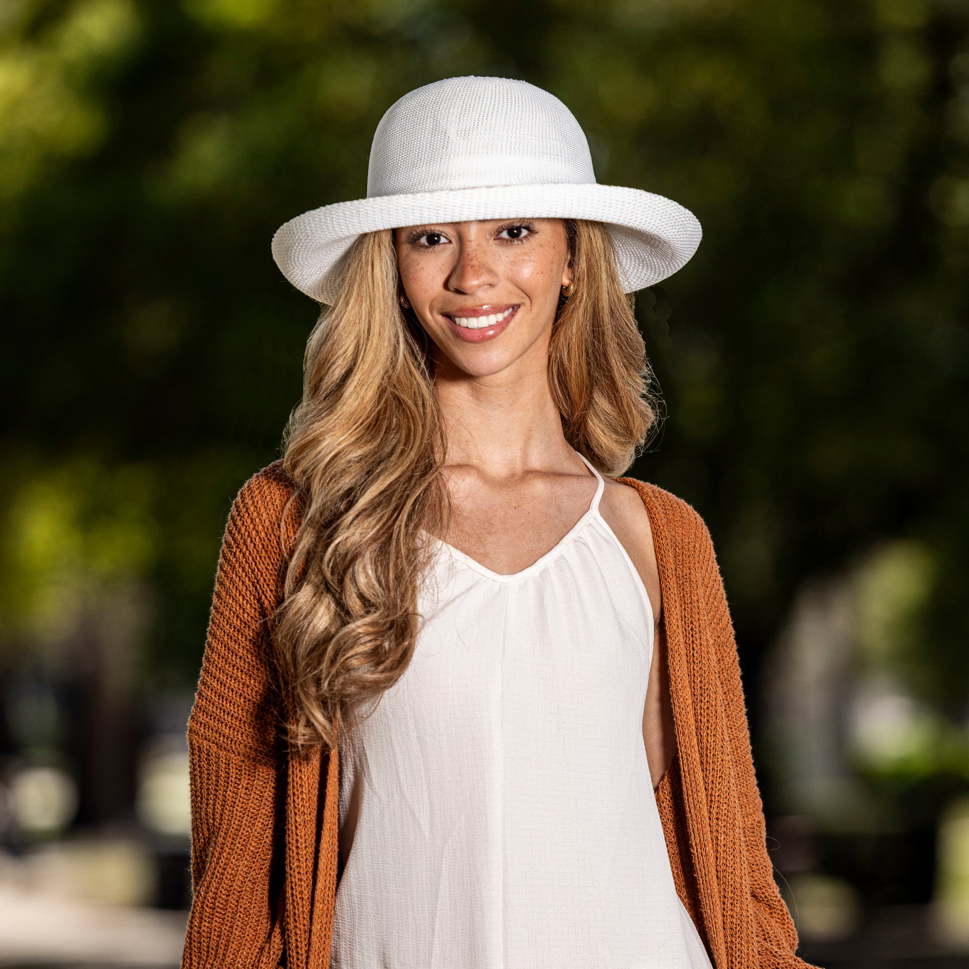 Woman wearing a Victoria UPF wide brim sun protection hat and brown cardigan, White