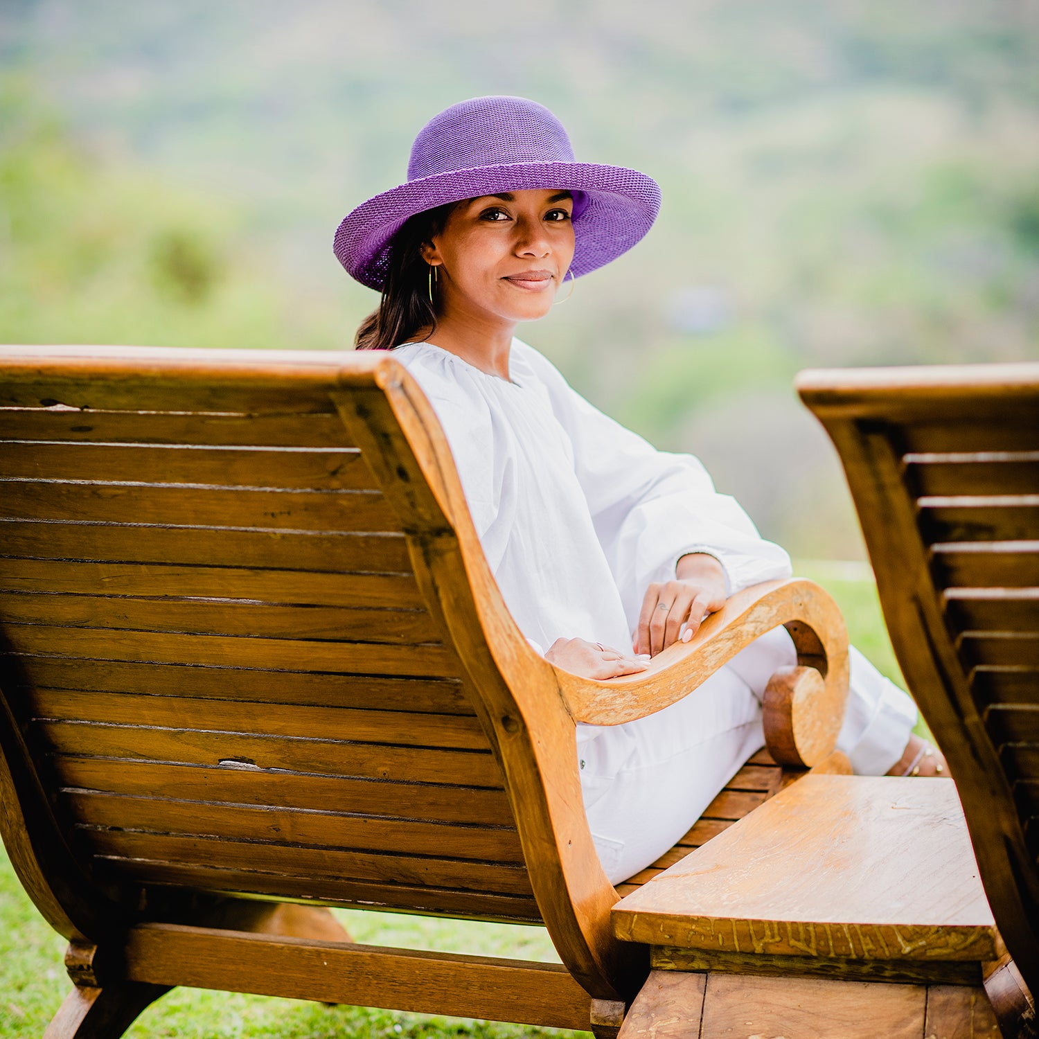 Woman taking in the view from a resort balcony, wearing the Wallaroo Victoria Sun Hat, a best-selling poly-straw hat perfect for sunny escapes, Deep Lilac